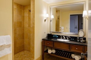 A bathroom with a shower, a sink, a mirror, and towels.
