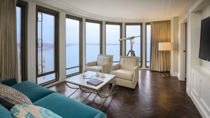 A spacious room with a large window, a sofa, a coffee table, and a lamp.