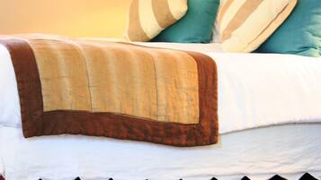 A hotel room with a bed, pillows, and a lamp.