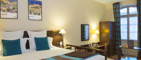 A hotel room with a large bed, two bedside tables, a desk, a chair, and two lamps.