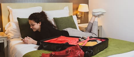 Ein Bett mit Koffer, Handtasche und Schuhpaar daneben.