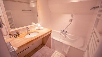 Een badkamer met een houten wastafel, een wastafel, een spiegel, een handdoek, een douche en een bad.
