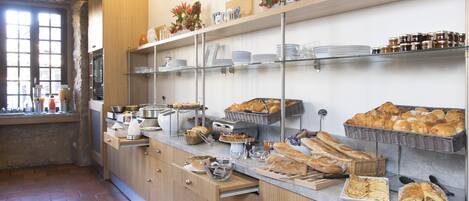 A breakfast buffet with various pastries, bread, and condiments.
