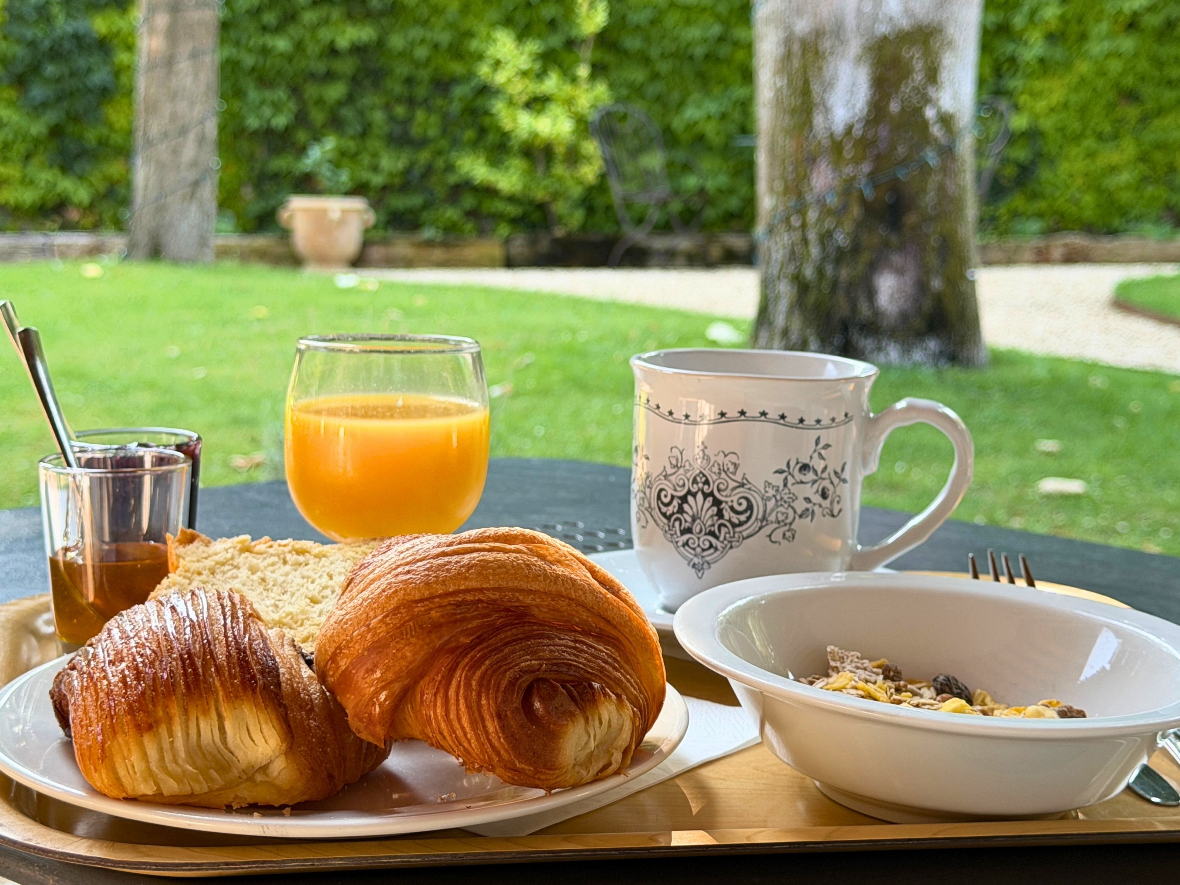 Desayuno con cruasanes, zumo de naranja, café y una taza sobre una mesa.
