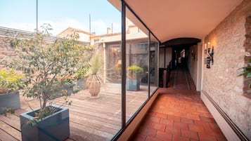 Een modern interieur met een houten terras, planten in potten en een stenen muur.