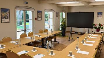 A conference room with long tables, chairs, a projector screen, and framed pictures on the walls.