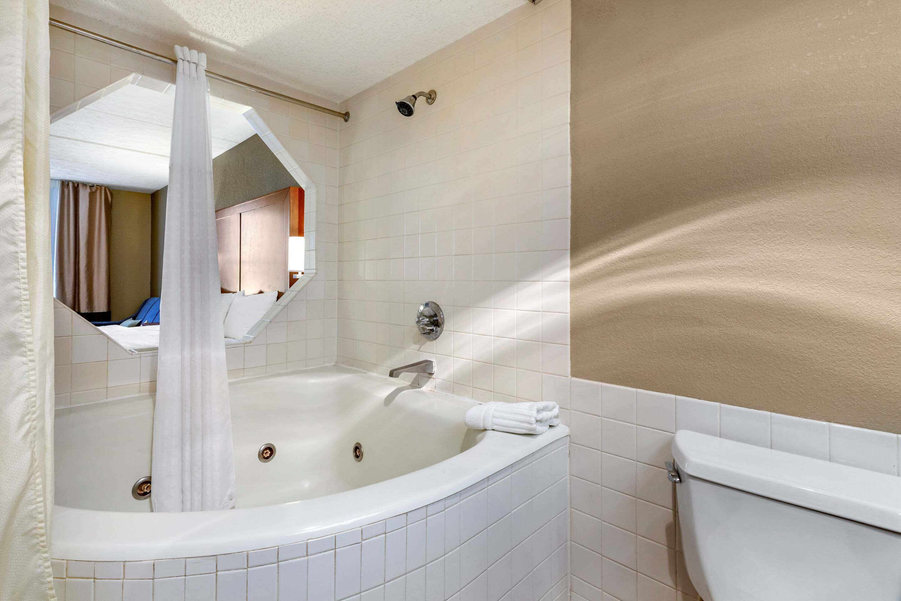 Un baño con una bañera, un inodoro y un espejo.