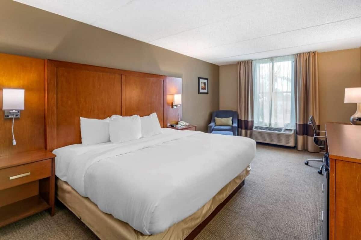 Une chambre d’hôtel avec un grand lit, un bureau, une chaise et une lampe de bureau.