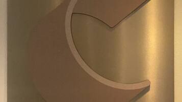 A metallic wall with a large, abstract, crescent-shaped cutout.