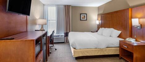 A hotel room with a bed, a desk, a television, and a nightstand.