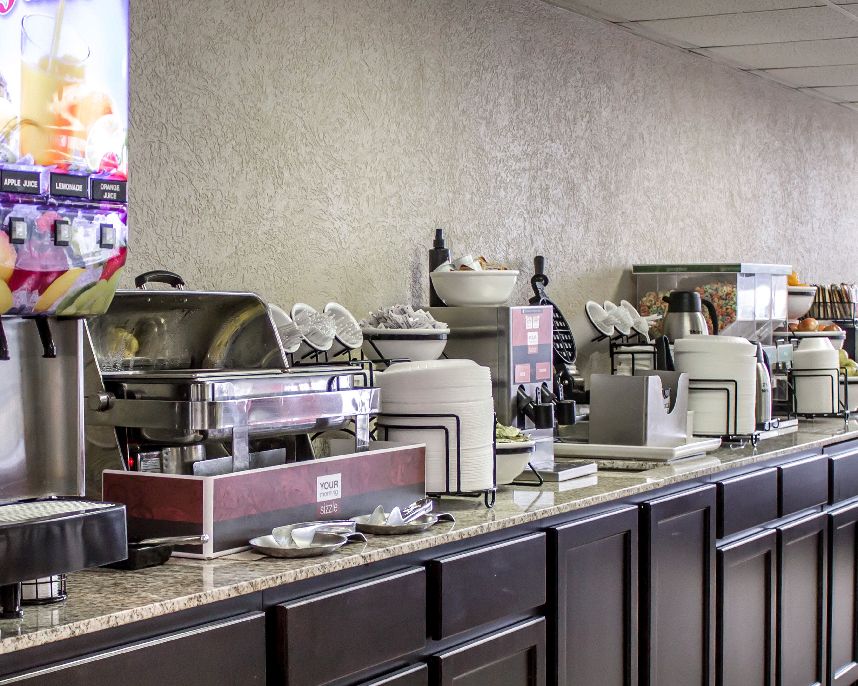 Un buffet proposant différents postes de service, notamment un distributeur de boissons, un bar à salades et des plats chauds.