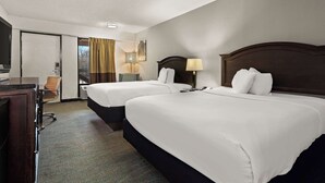 A hotel room with two beds, a desk, a chair, and a sliding door leading to a balcony. - Rodeway Inn Lumberton Central (Lumberton)