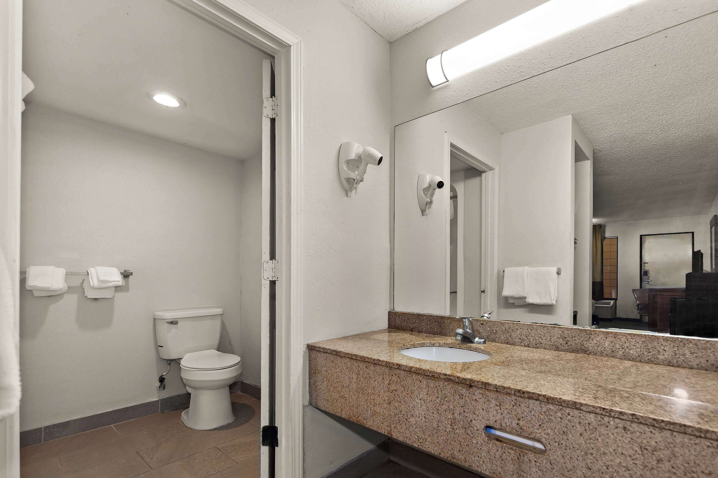A bathroom with a toilet, sink, and mirror.