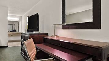 Een hotelkamer met een bureau, stoel, televisie en een grote spiegel.