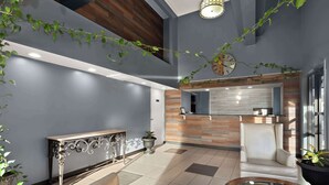 A modern lobby with a reception desk, seating area, and a clock on the wall. - Rodeway Inn Lumberton Central (Lumberton)