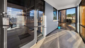 A modern hotel lobby with large glass doors, a tiled floor, and a view of the outside. - Rodeway Inn Lumberton Central (Lumberton)