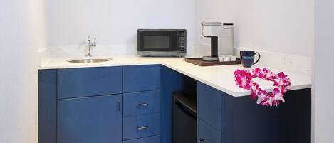 A compact kitchen with a microwave, coffee maker, and a sink.