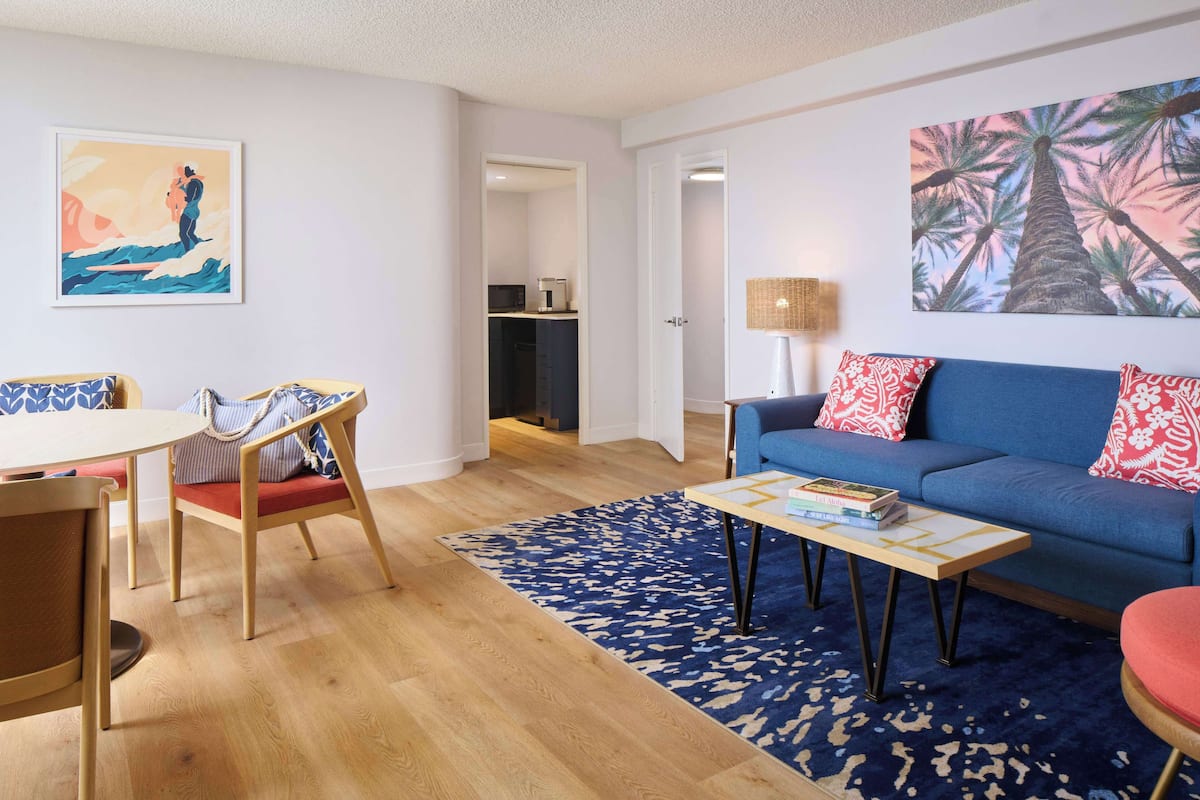 Un salon avec un canapé bleu, une table basse et un coin repas avec des chaises.