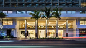 Een modern hotel met een opvallende ingang, meerdere verdiepingen en een balkon.
