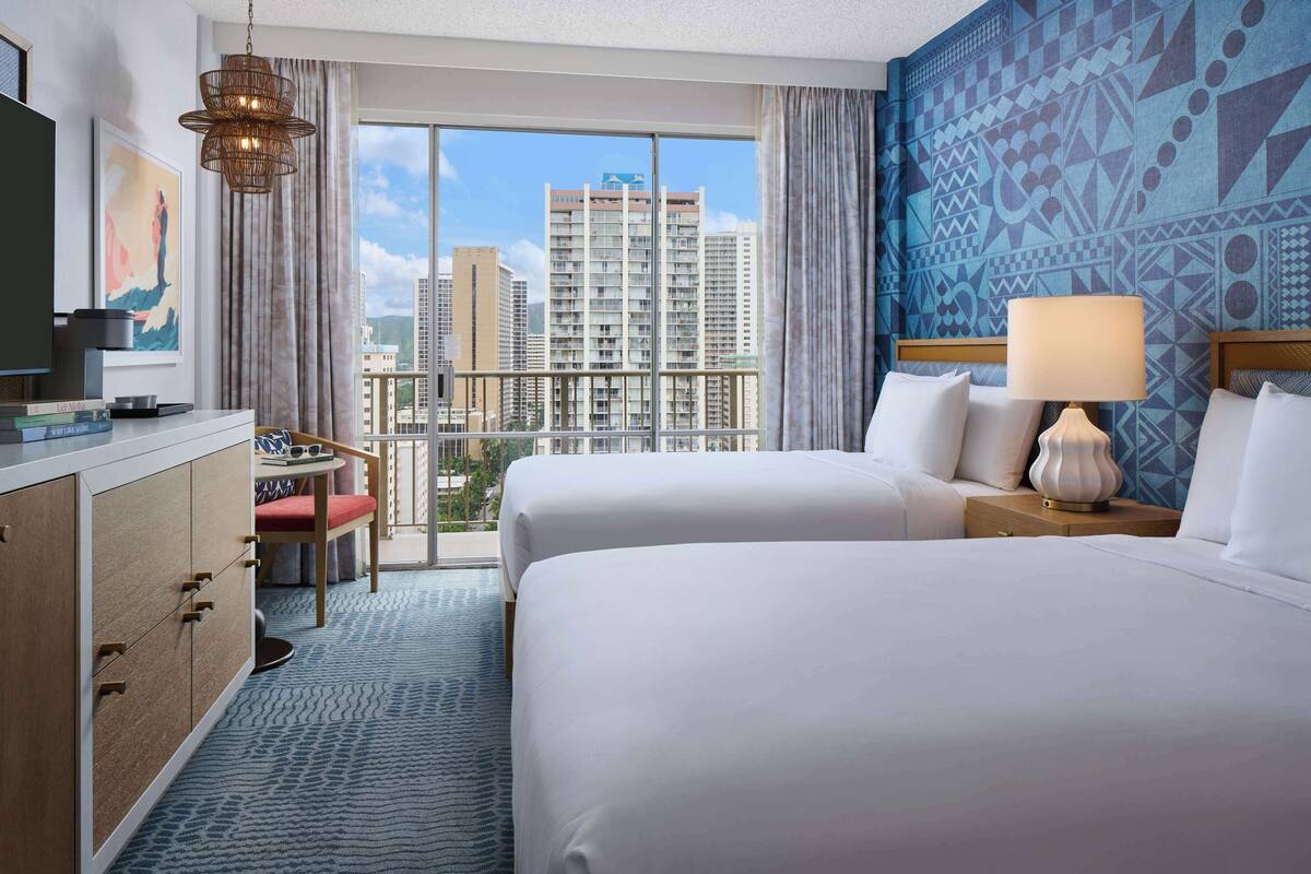 Une chambre d’hôtel avec deux lits, une télévision, un bureau et une vue sur la ville.