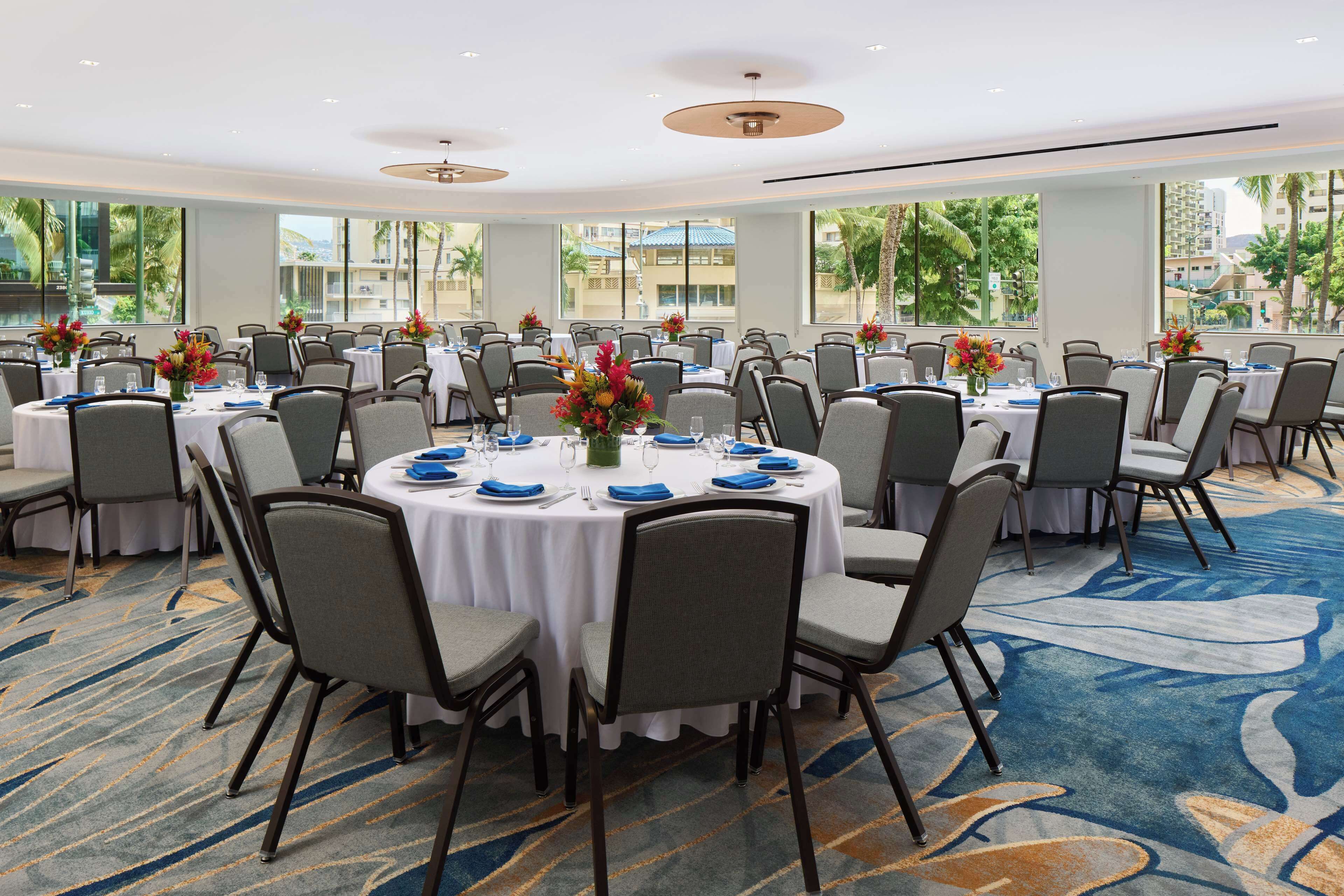 A conference room with round tables, chairs, and floral centerpieces.
