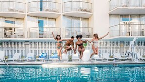 Une piscine avec des chaises longues et, au fond, un bâtiment doté de balcons.