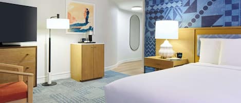 A hotel room with a bed, a desk, a television, a lamp, and a painting on the wall.