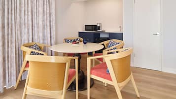 A dining area with a round table, four chairs, a microwave, and a white door.