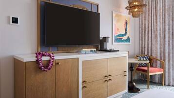 Habitación de hotel con televisor, un aparador de madera, una silla y un adorno en la pared.