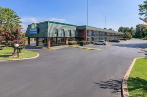 Un hotel Days Inn by Wyndham con techo verde, varios pisos y un estacionamiento con varios autos.