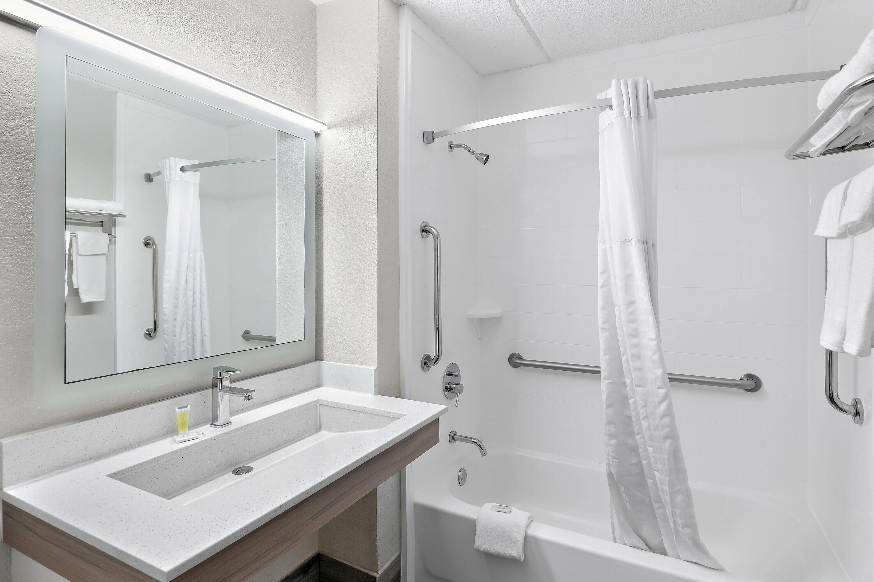 Un baño moderno con lavamanos doble, un espejo grande, ducha con puerta de cristal y un perchero para toallas.