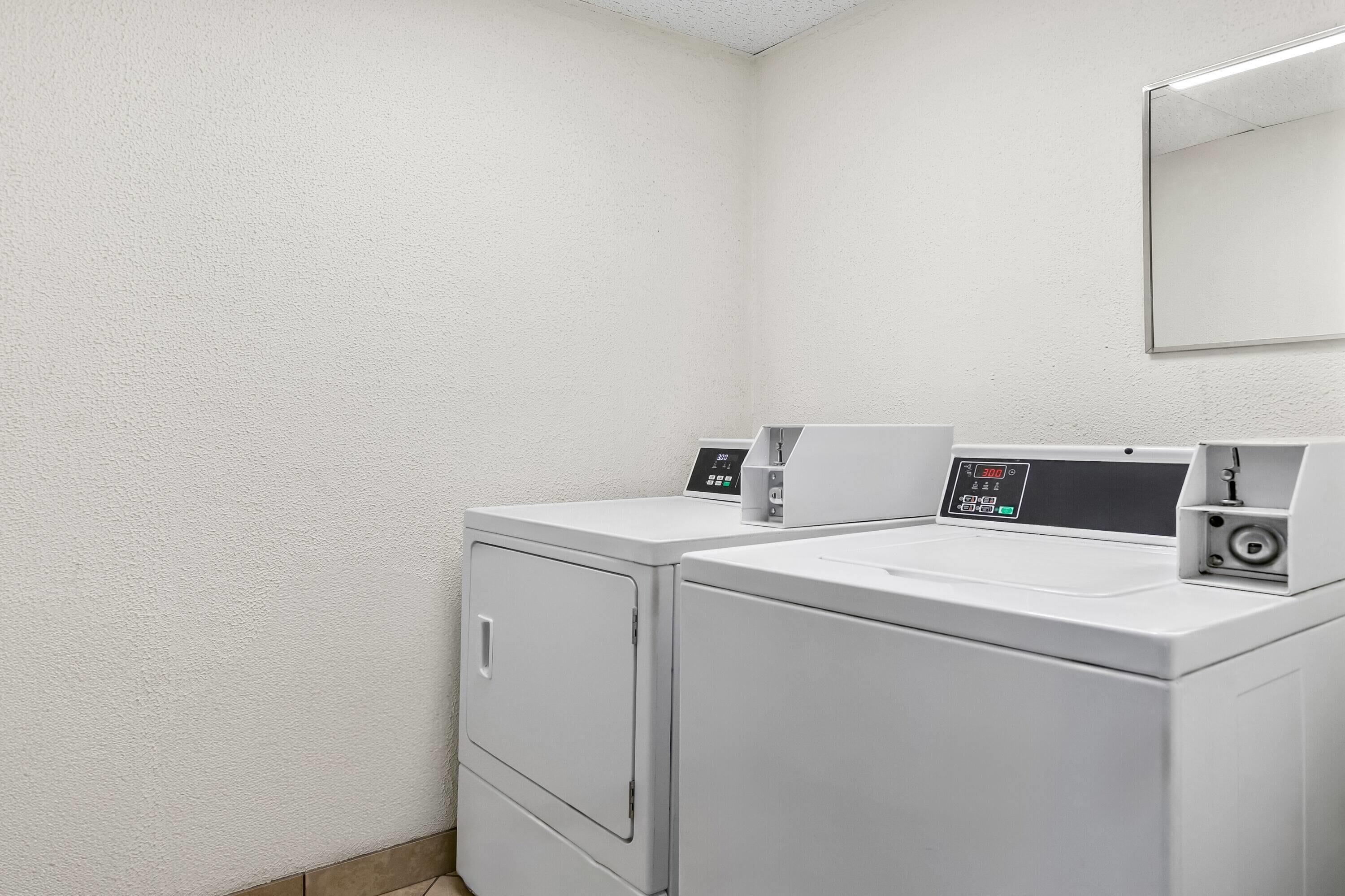 A laundry area with two white washing machines and a control panel.