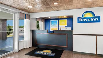 A Days Inn reception area with a modern design, including a reception desk, a large window, and a ceiling with a textured pattern.