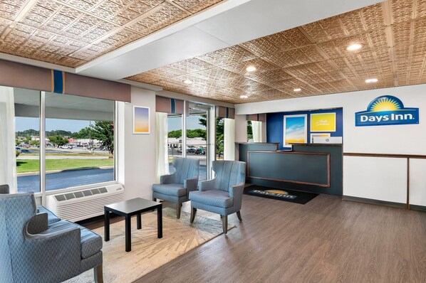 A Days Inn reception area with a view of the parking lot and trees.