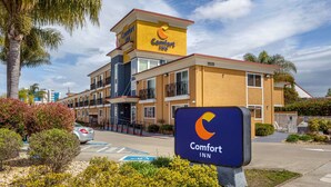 A Comfort Inn hotel with a yellow facade, multiple balconies, and a parking lot with a sign. - Comfort Inn Castro Valley (Castro Valley)