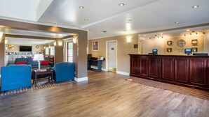 A spacious lobby with a wooden reception desk, a seating area with blue chairs, and a kitchen in the background. - Comfort Inn Castro Valley (Castro Valley)