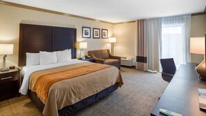 A hotel room with a large bed, a desk, a chair, a lamp, and a window with curtains. - Comfort Inn Castro Valley (Castro Valley)