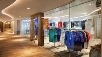 Una tienda de ropa moderna con suelo de madera y vitrinas de cristal.