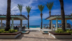 A beachside resort with a wooden deck, palm trees, and a view of the ocean. - The Westin Grand Cayman Seven Mile Beach Resort & Spa (Seven Mile Beach)