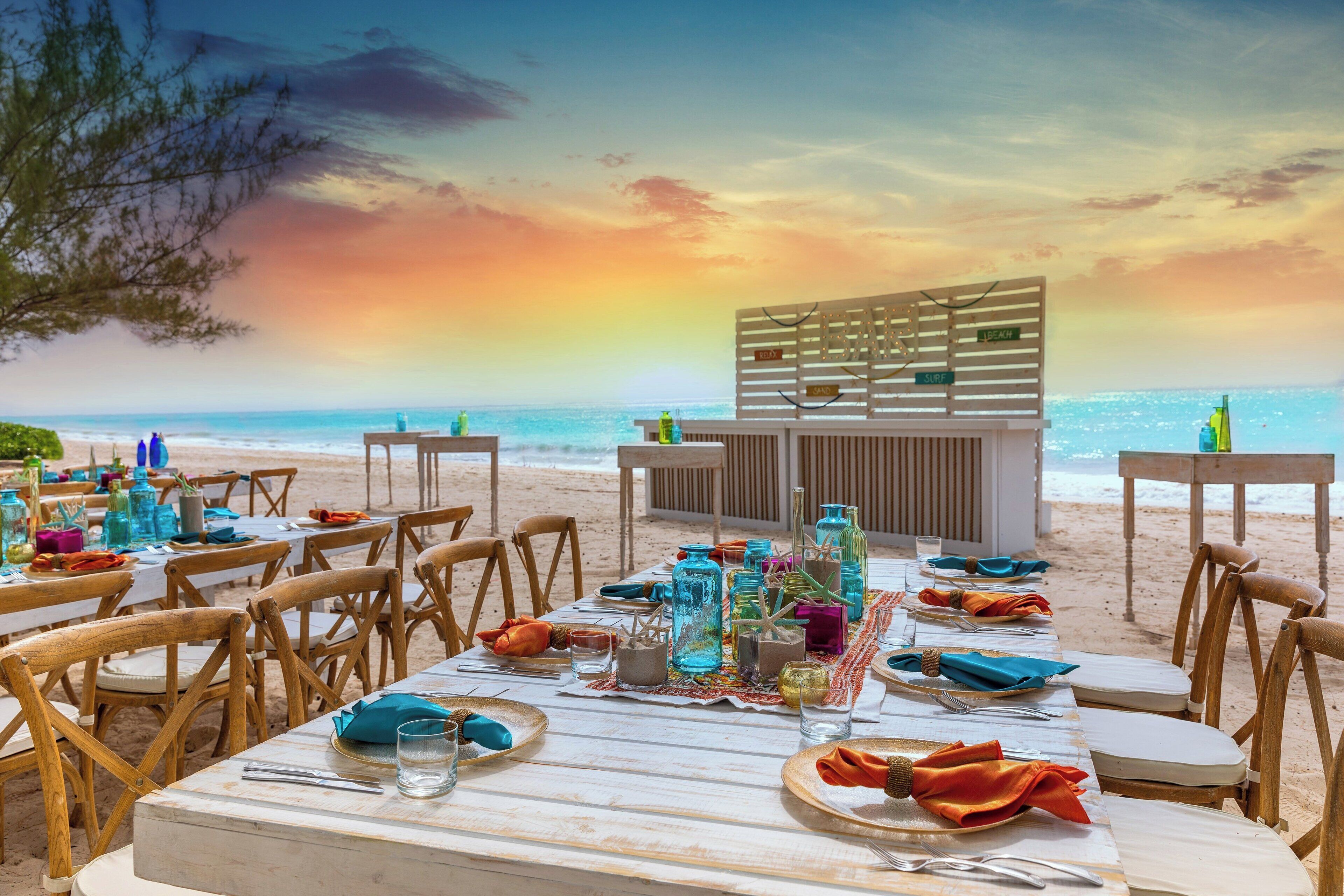 A beachside restaurant with tables set for dining, overlooking the ocean.