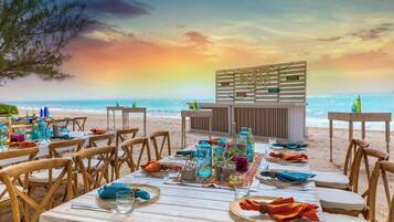A beachside restaurant with tables set for dining, overlooking the ocean.