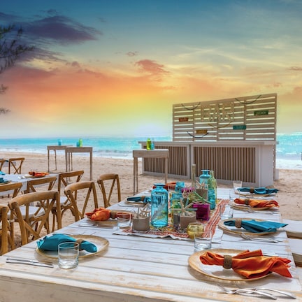 A beachside restaurant with tables set for dining, overlooking the ocean.