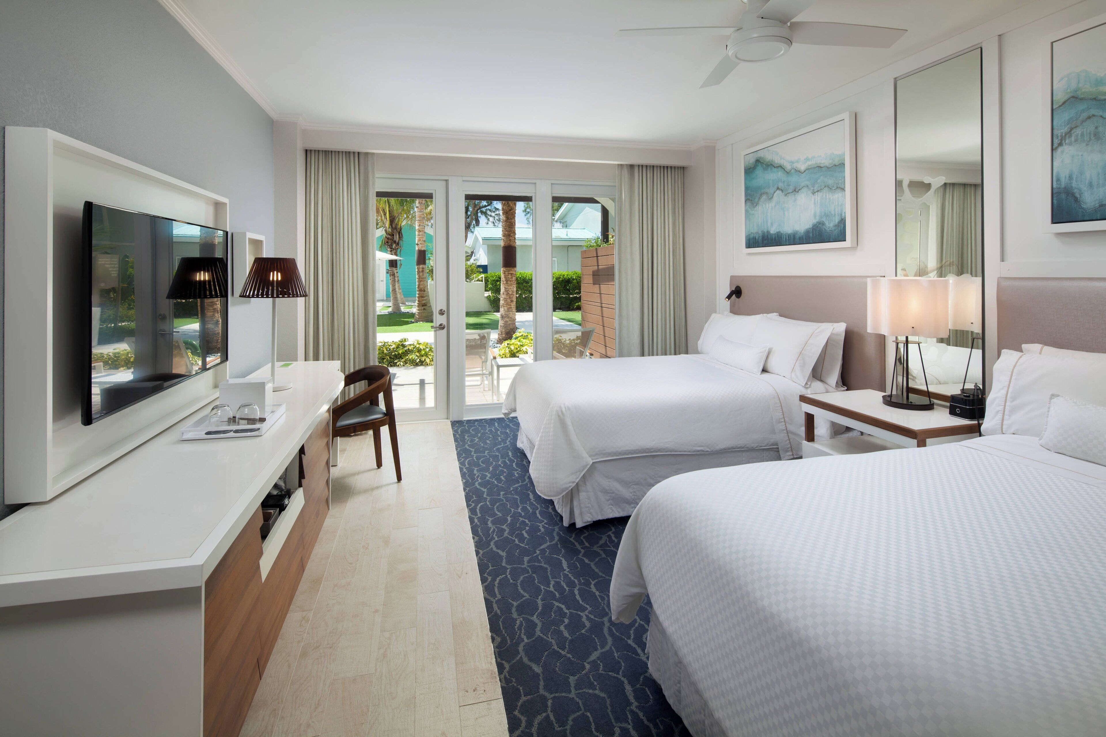Ein Hotelzimmer mit zwei Betten, einem Fernseher, einem Schreibtisch und Blick ins Freie.