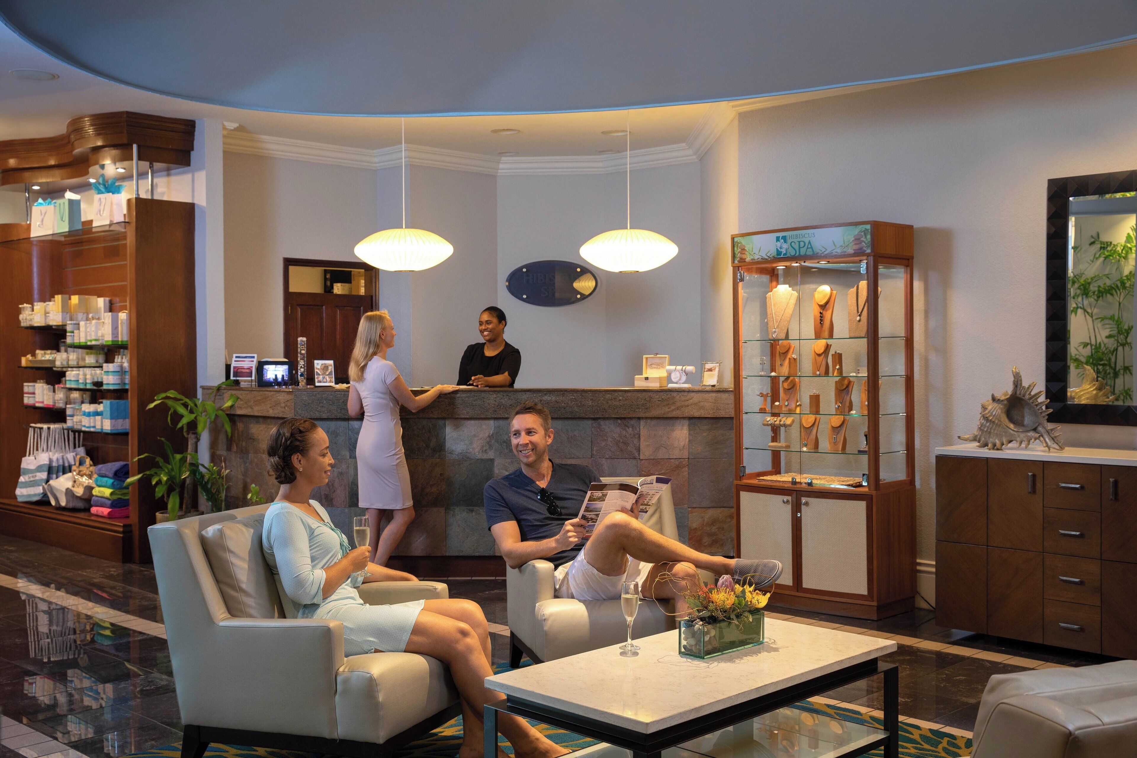 Un vestíbulo de hotel con zonas de estar, una recepción y una exposición de servicios de spa.