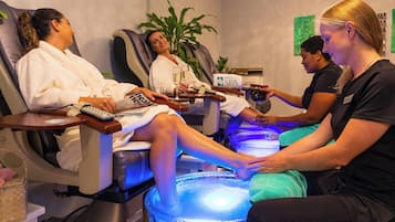 A spa setting with massage chairs, a foot bath, and a person receiving a foot massage.
