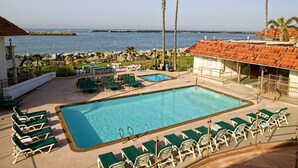 A pool area with lounge chairs and a view of the ocean. - Oceanside Marina Suites (Oceanside)