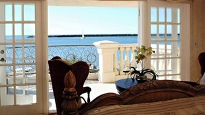 A balcony with a view of the sea, a chair, a table, and a bed. - Oceanside Marina Suites (Oceanside)