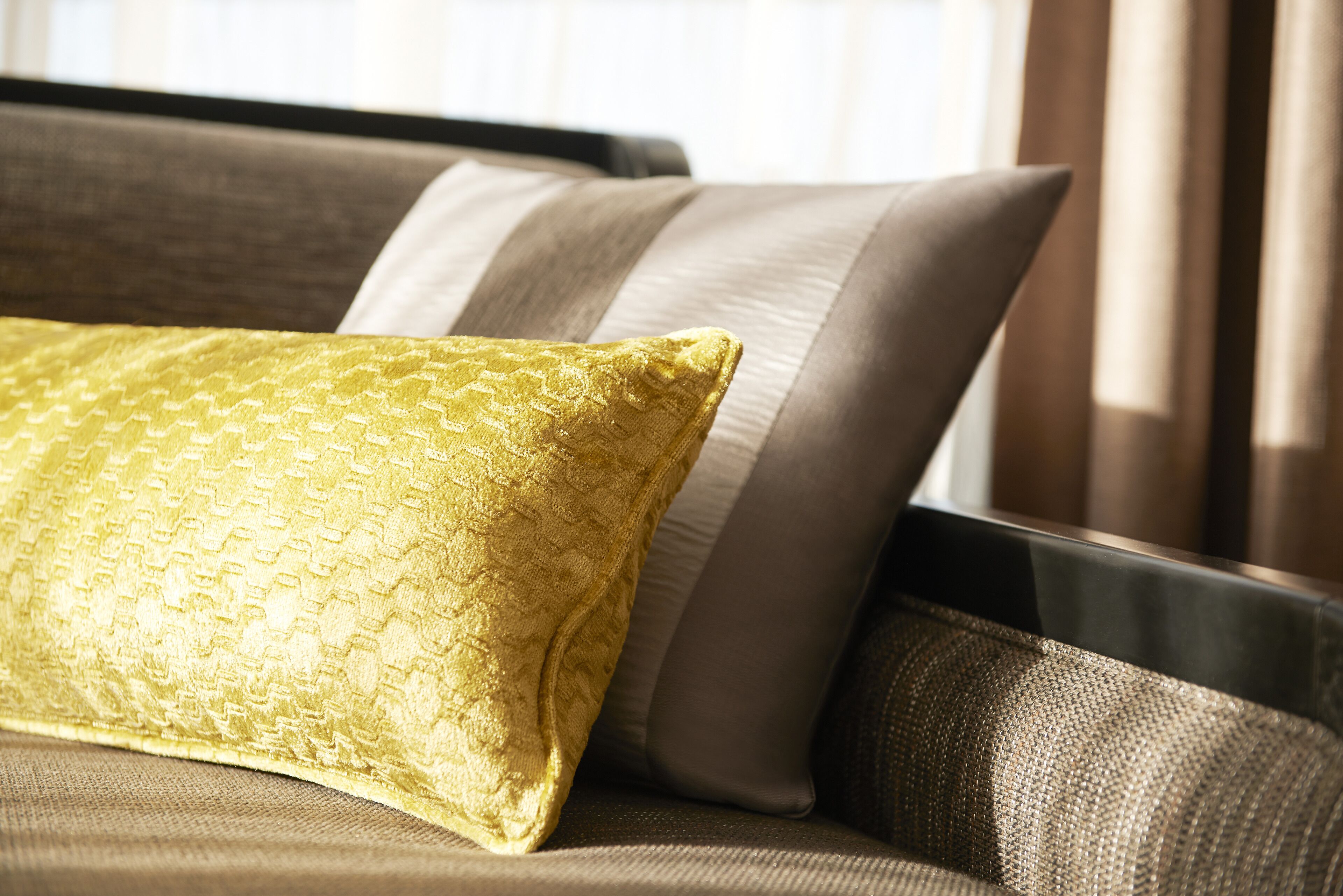 A close-up of a sofa with a patterned cushion and a smooth, solid-colored cushion.