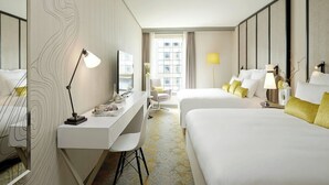 A hotel room with a desk, two beds, a chair, and a large window. - Renaissance Paris La Defense Hotel (Puteaux)