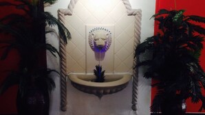 Ein Badezimmer mit weiß gefliesten Wänden, einem zentralen Waschbecken mit dekorativer Armatur und zwei Blumentöpfen.
